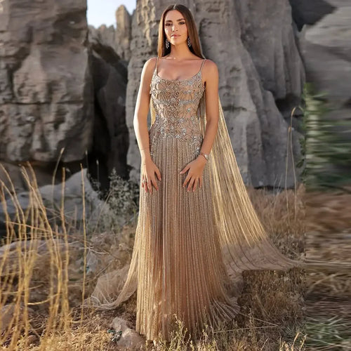 Woman in a sparkling evening gown standing in a natural setting with rocks and dry grass.